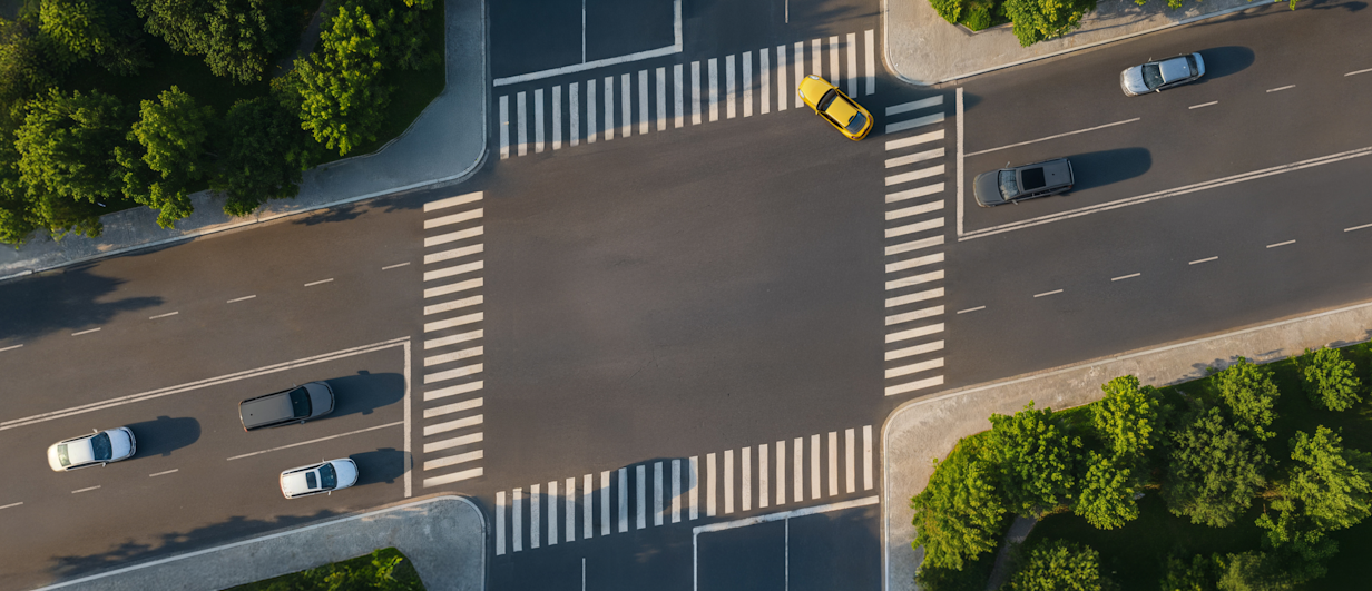 Aerial view of a street intersection where the crosswalks form a slanted parallelogram, imitating the SynaPay logo.